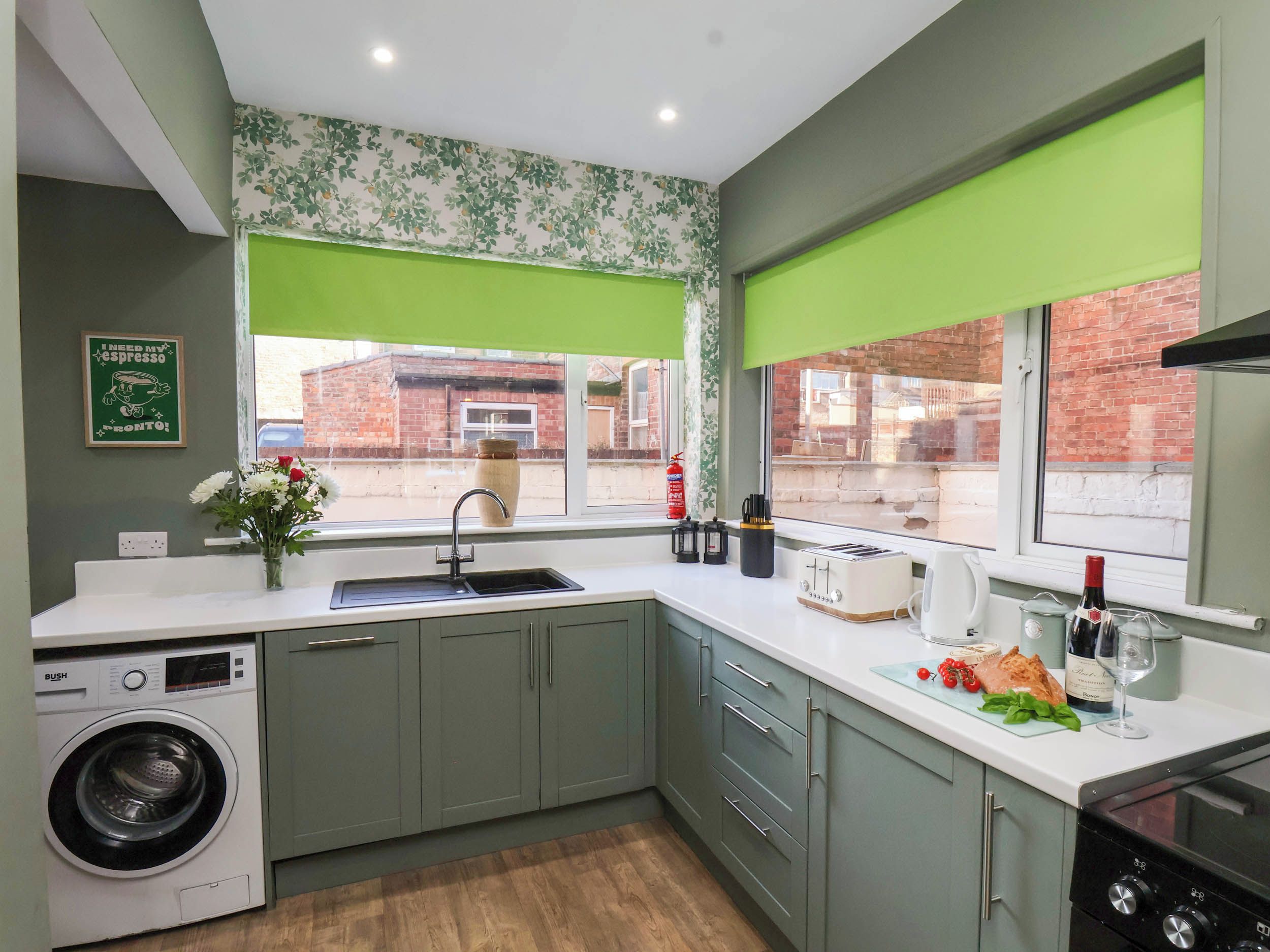 A compact kitchen with a washing machine, a sink, a toaster, and a stove.