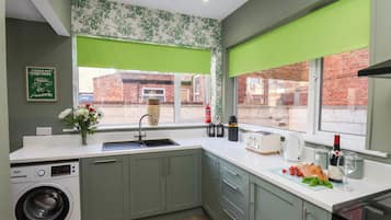 A compact kitchen with a washing machine, a sink, a toaster, and a stove.