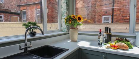 A kitchen with a sink, a vase with sunflowers, and a window with a view of brick buildings.