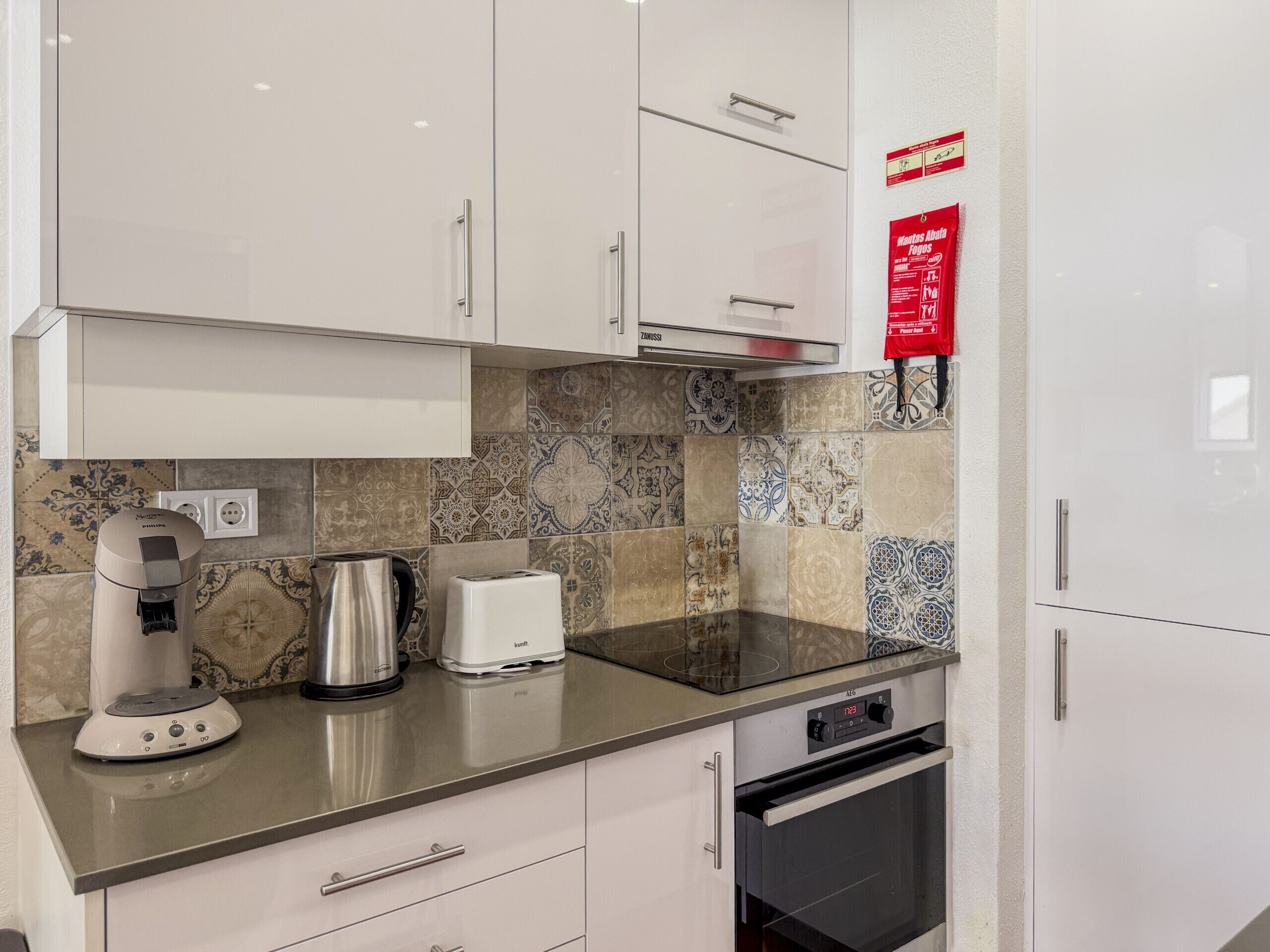 A modern kitchen with white cabinets, a coffee maker, a toaster, and a built-in oven.