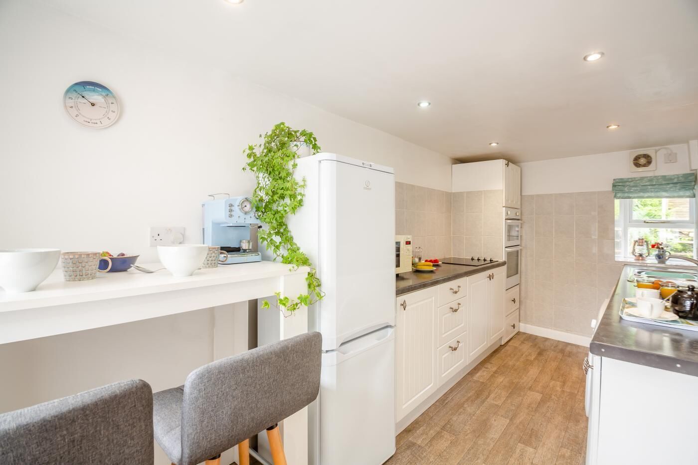 Ett modernt kök med vita skåp, en kaffemaskin och en växt.