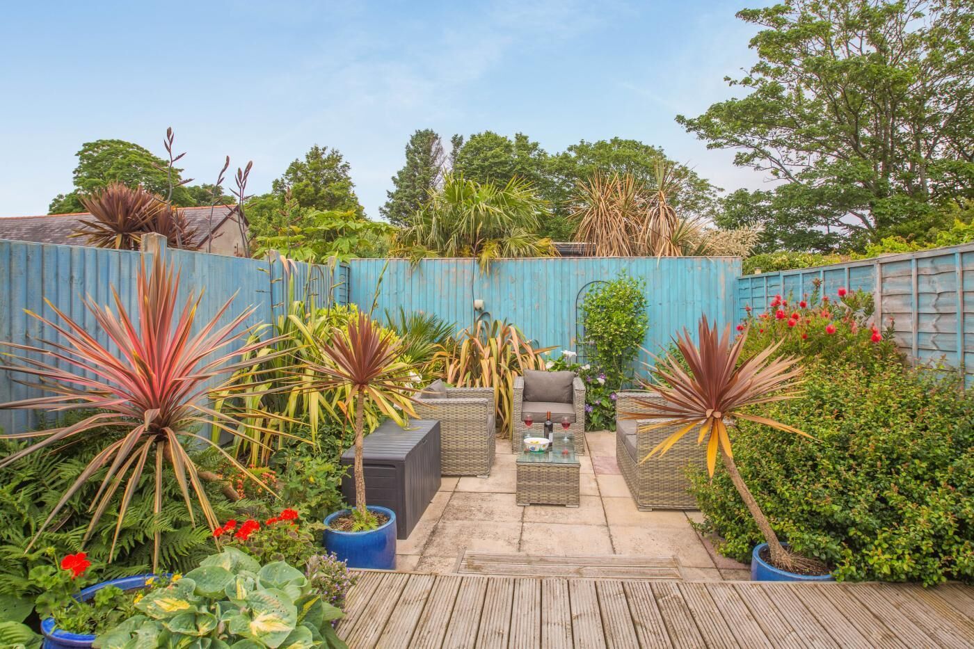 A patio area with outdoor furniture, potted plants, and a wooden deck.