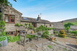 A stone building with a garden patio, a chimney, and a small tree. - 1 Bed in Richmond (oc-44401) (Healaugh)