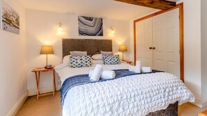 Una camera da letto con un letto, due comodini, una testiera, una porta e un'opera d'arte appesa al muro.