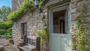 Un edificio in pietra con una porta verde, una panchina e piante in vaso.