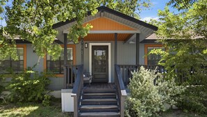 Une maison moderne avec un porche à l’avant, des marches en bois et une porte.