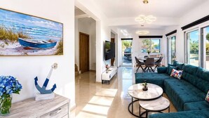 Una sala moderna con sofá, mesa de centro y un cuadro de un barco en la playa.
