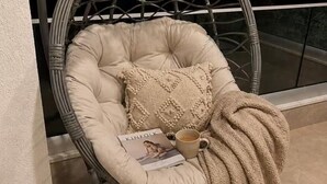Una silla cómoda con una revista y una taza, cerca de una ventana con vistas.
