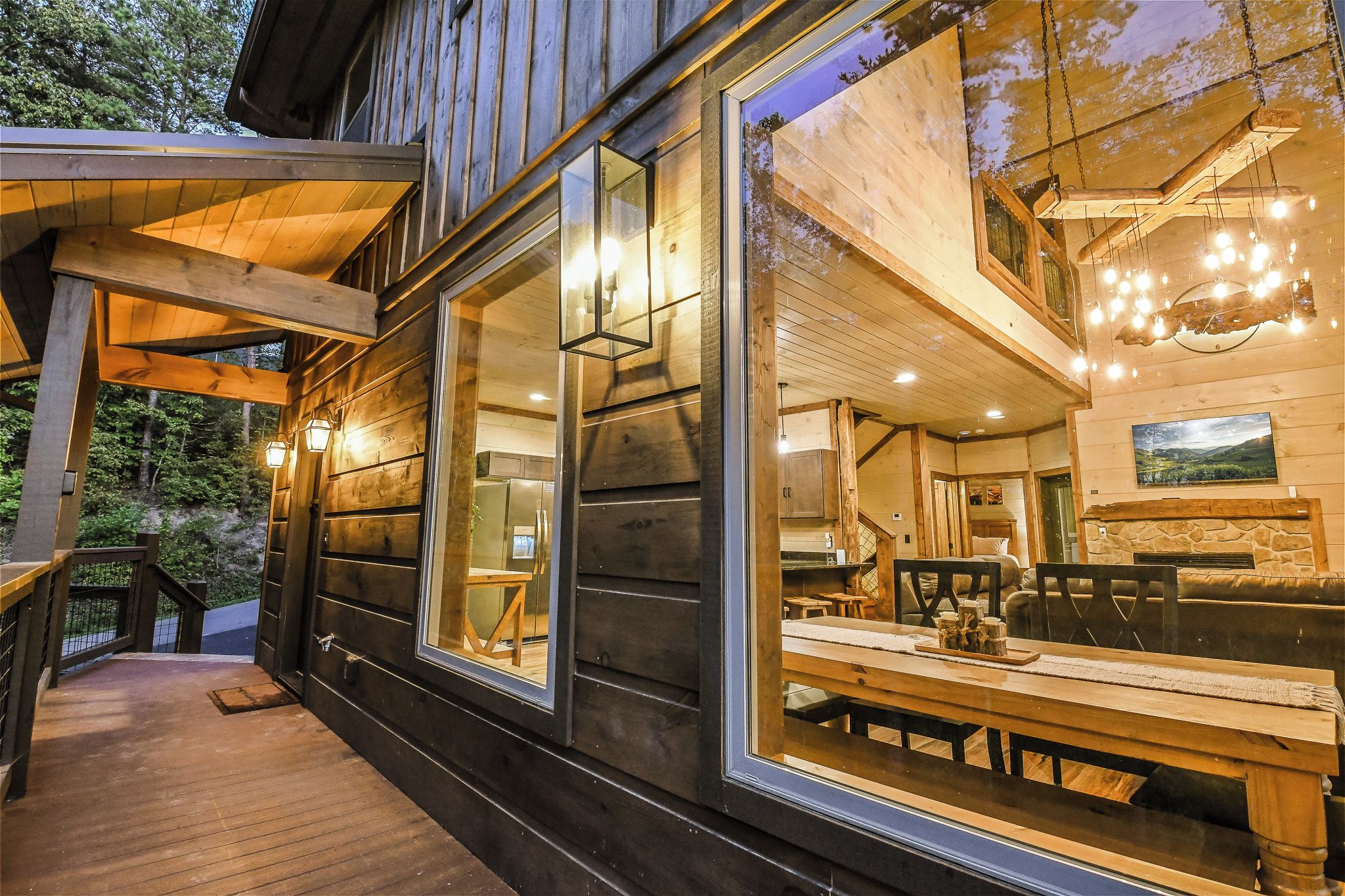 Una cabaña de madera con un ventanal grande, una zona de comedor con mesa y sillas, y una chimenea de piedra.