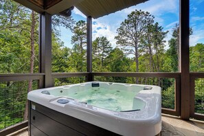 A hot tub on a wooden deck with a view of a forest. - Forest Views, Hot Tub, Fireside Nights, Theater room & Family Fun (Sevierville)