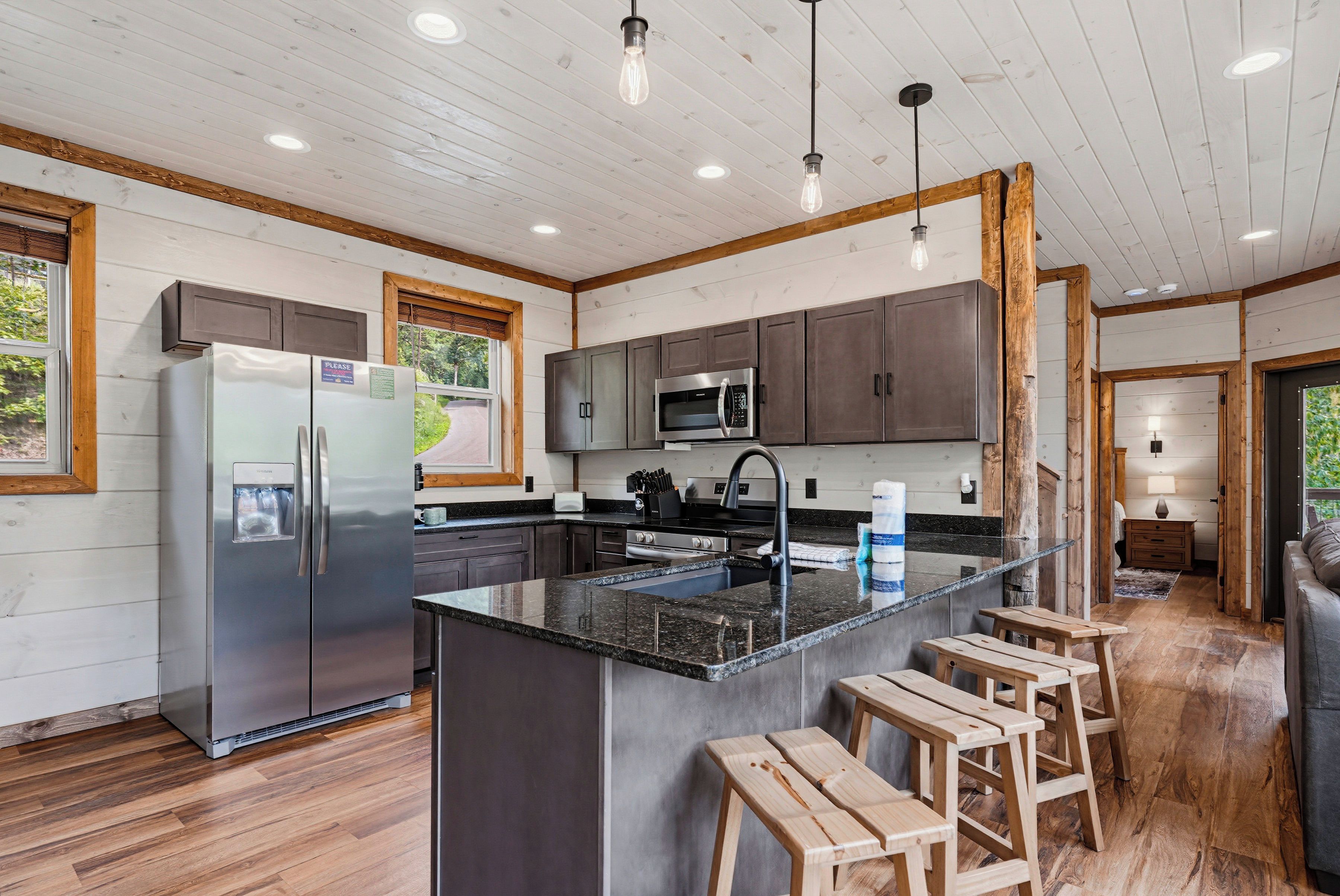 Une cuisine moderne dotée d’un réfrigérateur en acier inoxydable, d’un four à micro-ondes encastré et d’un plan de travail en granit.