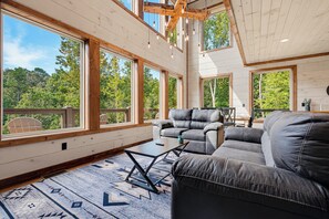Ein geräumiges Zimmer mit großen Fenstern, einem Sofa und einem Tisch.