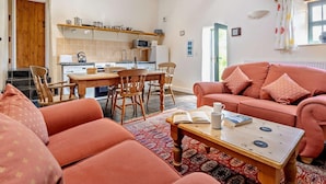 Ein gemütliches Wohnzimmer mit einer Couch, einem Couchtisch und einem Essbereich mit Stühlen sowie einer Küche im Hintergrund.