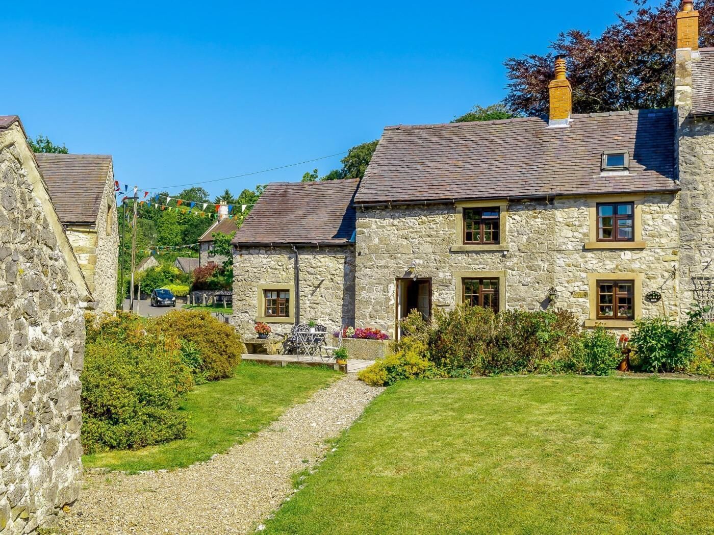 A stone house with a paved driveway and a lawn.
