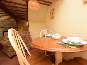 A dining area with a round wooden table, a patterned armchair, and a stone fireplace. - 1 Bed in Eyam (oc-pk478) (Eyam)