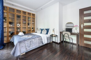 A bedroom with a bed, a wooden wardrobe, a desk with a chair, and a mirror. - Lumina 2BR Apart with Two Patio  (Warszawa)