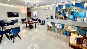 Un interior moderno con una zona de bar, asientos y un televisor de pantalla plana.