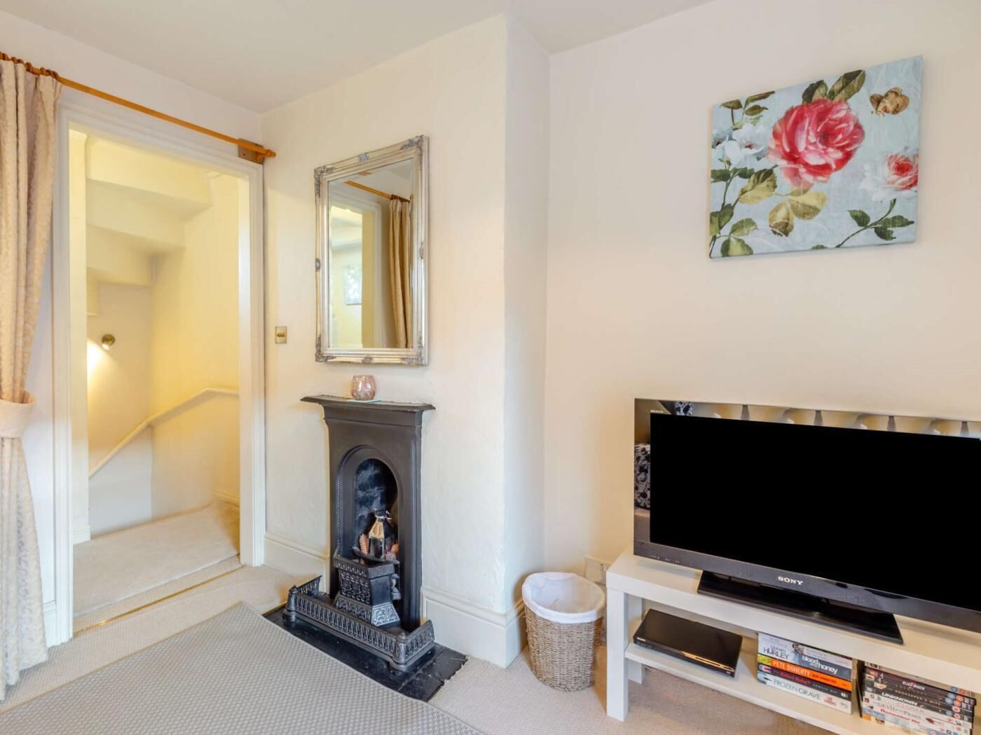 A living room with a fireplace, a television, and a floral painting on the wall.