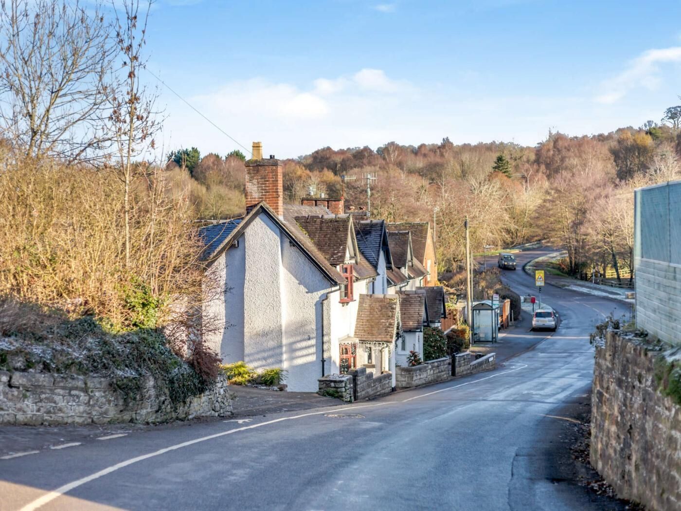 A narrow road with houses on one side and a bridge in the distance.