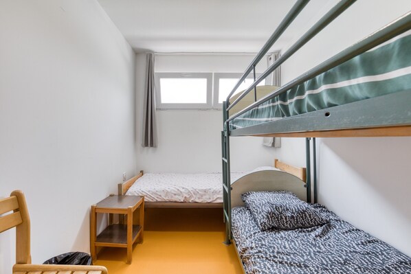 Une chambre de dortoir avec des lits superposés, un bureau, une chaise et une fenêtre.