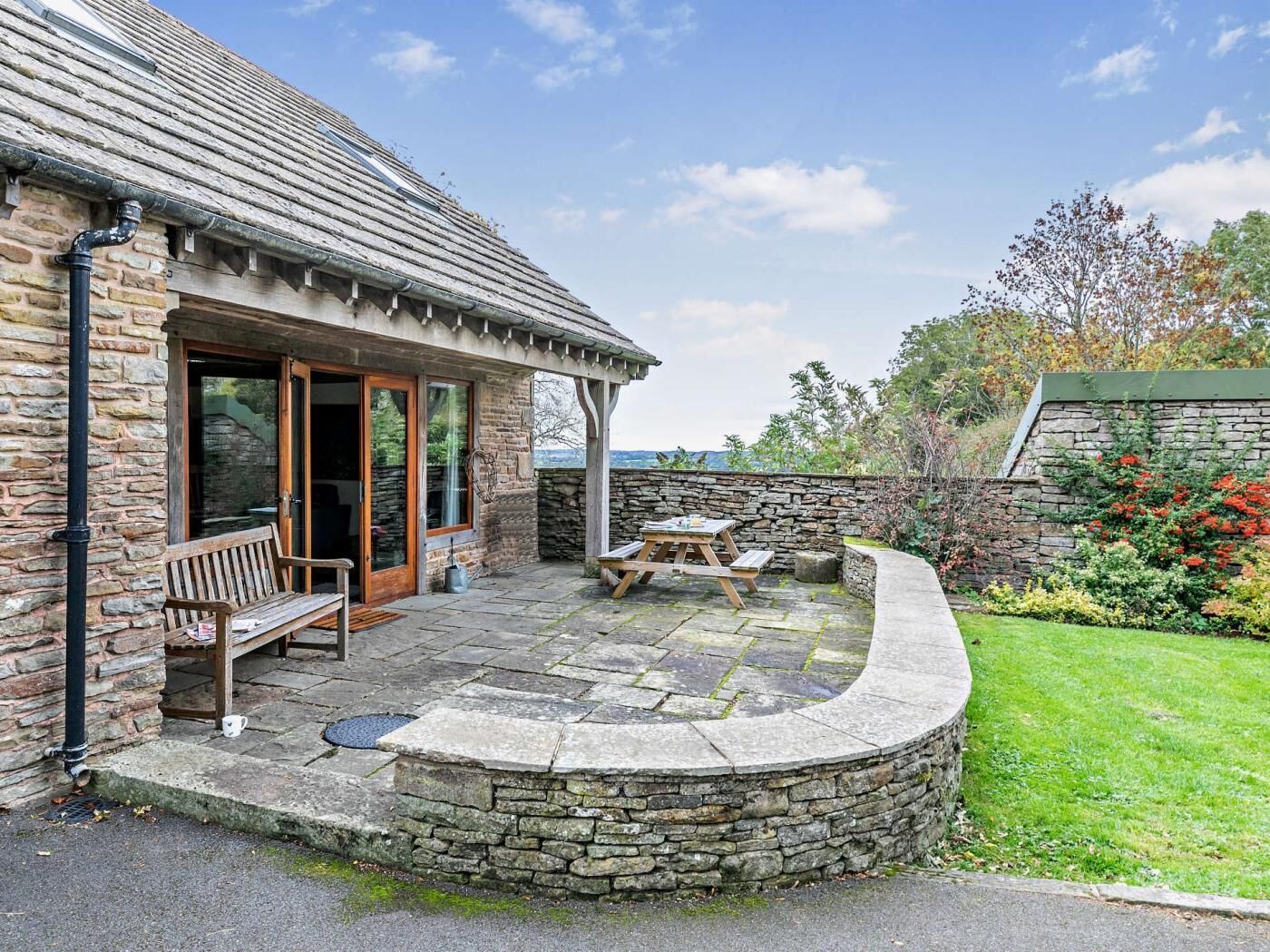 A stone building with a patio, a bench, and a table.