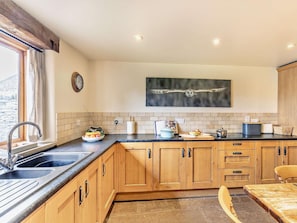 A kitchen with a stone backsplash, wooden cabinets, a black countertop, and a window with curtains. - 2 Bed in Barlow (oc-pk801) (Barlow)