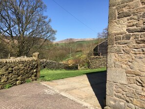 A stone building with a stone wall and a grassy area with trees. - 2 Bed in High Peak (oc-pk551) (Hayfield)