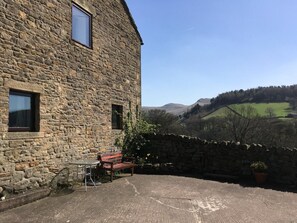 A stone building with a patio area, a table, and a bench. - 2 Bed in High Peak (oc-pk551) (Hayfield)