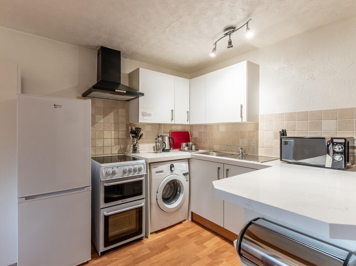 A compact kitchen with a refrigerator, stove, oven, microwave, and washing machine.