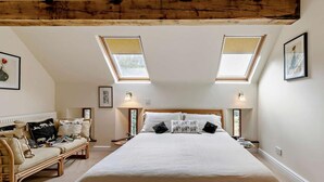 Ein Schlafzimmer mit einem großen Bett, zwei Nachttischen, einem Sofa und einem Oberlicht.