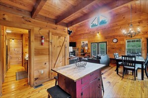 A wooden cabin interior with a dining area, kitchen, and living space. - Twin Cub Lodge, 3 Br, 2 Ba, Sleeps 8 & Hot Tub (Townsend)
