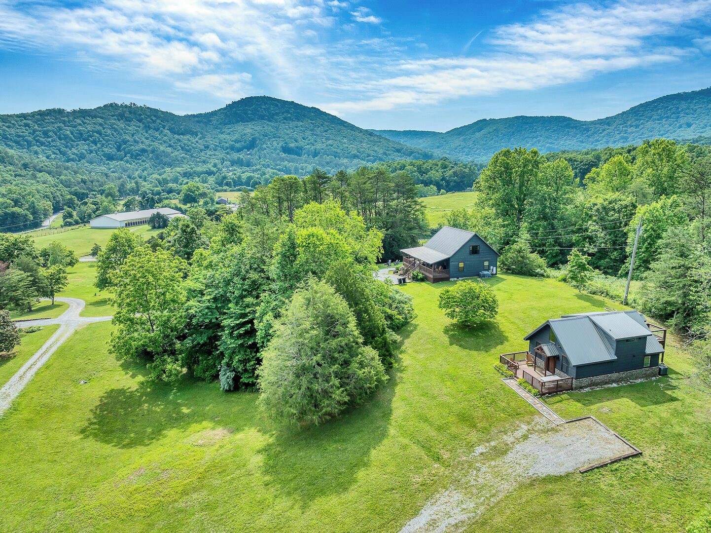 A rural property with a large house, a barn, and surrounding greenery.