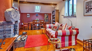 Un salon chaleureux avec une cheminée en pierre, un canapé rouge, des meubles en bois et une bibliothèque.