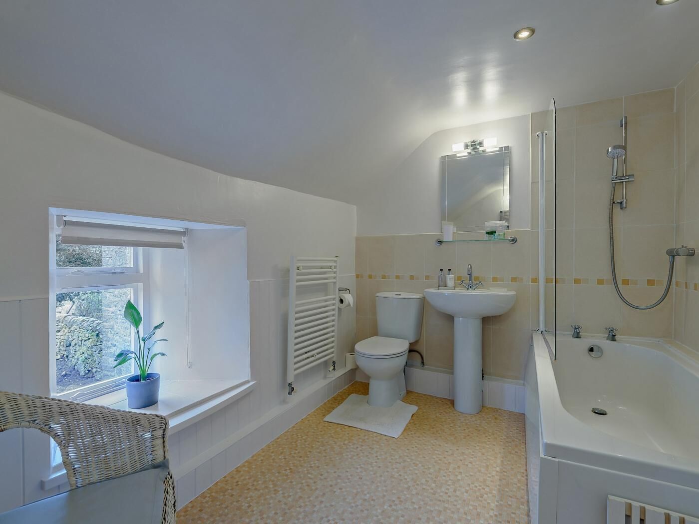 A bathroom with a toilet, sink, shower, and a window with a plant.