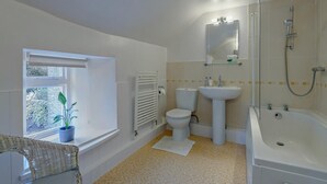 Ein Badezimmer mit Toilette, Waschbecken, Dusche und einem Fenster mit Pflanze.