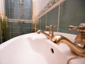 A bathroom with a white sink, a brass faucet, and a shower area with a glass door. - 1 Bed in Bakewell (oc-pk547) (Ashford in the Water)