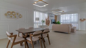 Et moderne spiseområde med et træbord og stole, en sofa og dekorative billeder på væggen.