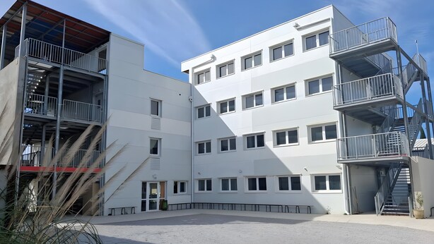 A multi-story building with a central courtyard, external staircases, and a flat roof. - Room with Shared Terrace and Wi-Fi, 10 Minutes from the Beach (Mudaison)