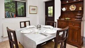 A dining area with a table set for four, chairs, a radiator, a bookshelf, and a door with a window. - 2 Bed in Holmesfield (oc-pk783) (Dronfield)