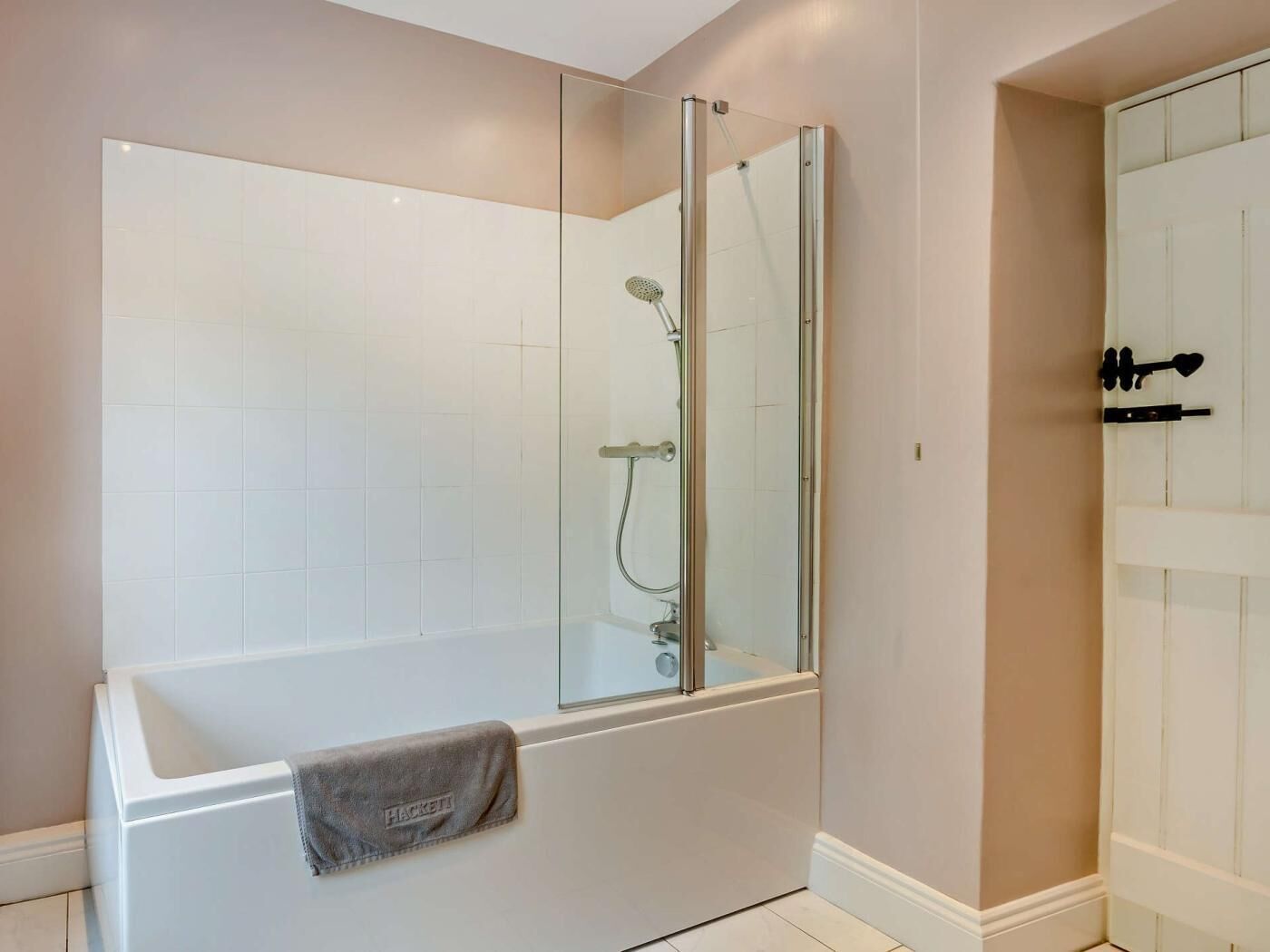 A modern bathroom with a glass-enclosed shower, a white bathtub, and a towel rack.