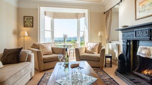 A cozy living room with a fireplace, two sofas, a coffee table with chess pieces, and a view through a large window. - 4 Bed in Matlock (oc-pk861) (Holloway)