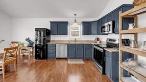 Una cocina moderna con armarios oscuros, electrodomésticos de acero inoxidable y una mesa de comedor de madera.