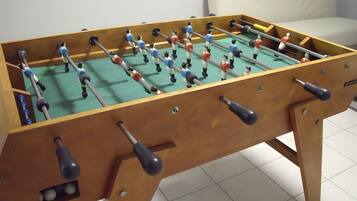 Una mesa de futbolín de madera con varios jugadores y un porta-balones.
