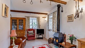 Una sala de estar acogedora con chimenea, televisor, estantería y un sillón rojo.