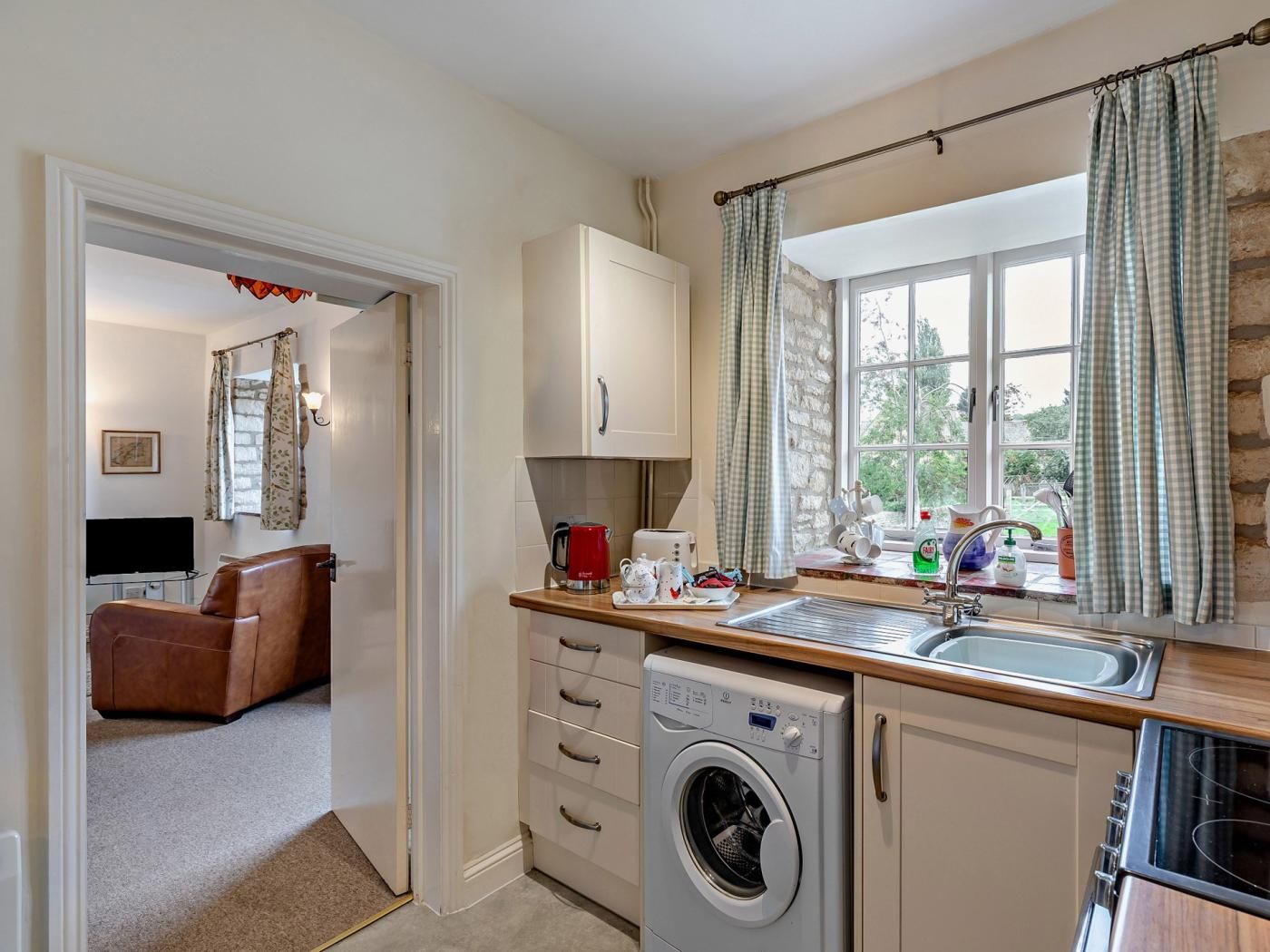A compact kitchen with a washing machine, a coffee maker, and a sink.