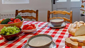 A dining table with a red and white checkered tablecloth, a bowl of grapes, a bowl of cherry tomatoes, a bowl of soup, and a loaf of bread. - 3 Bed in Baslow (oc-pk917) (Baslow)