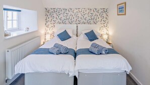A double bed with white and blue bedding, a window with a view, a radiator, and a blue pendant light. - 3 Bed in Baslow (oc-pk917) (Baslow)