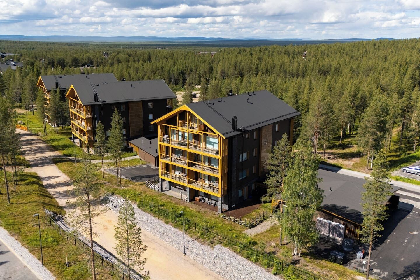 Useita kerroksia käsittävä majoitusrakennus, jonka keskellä on avoin sisäpiha, ja jonka ympärillä on tiheä metsä.