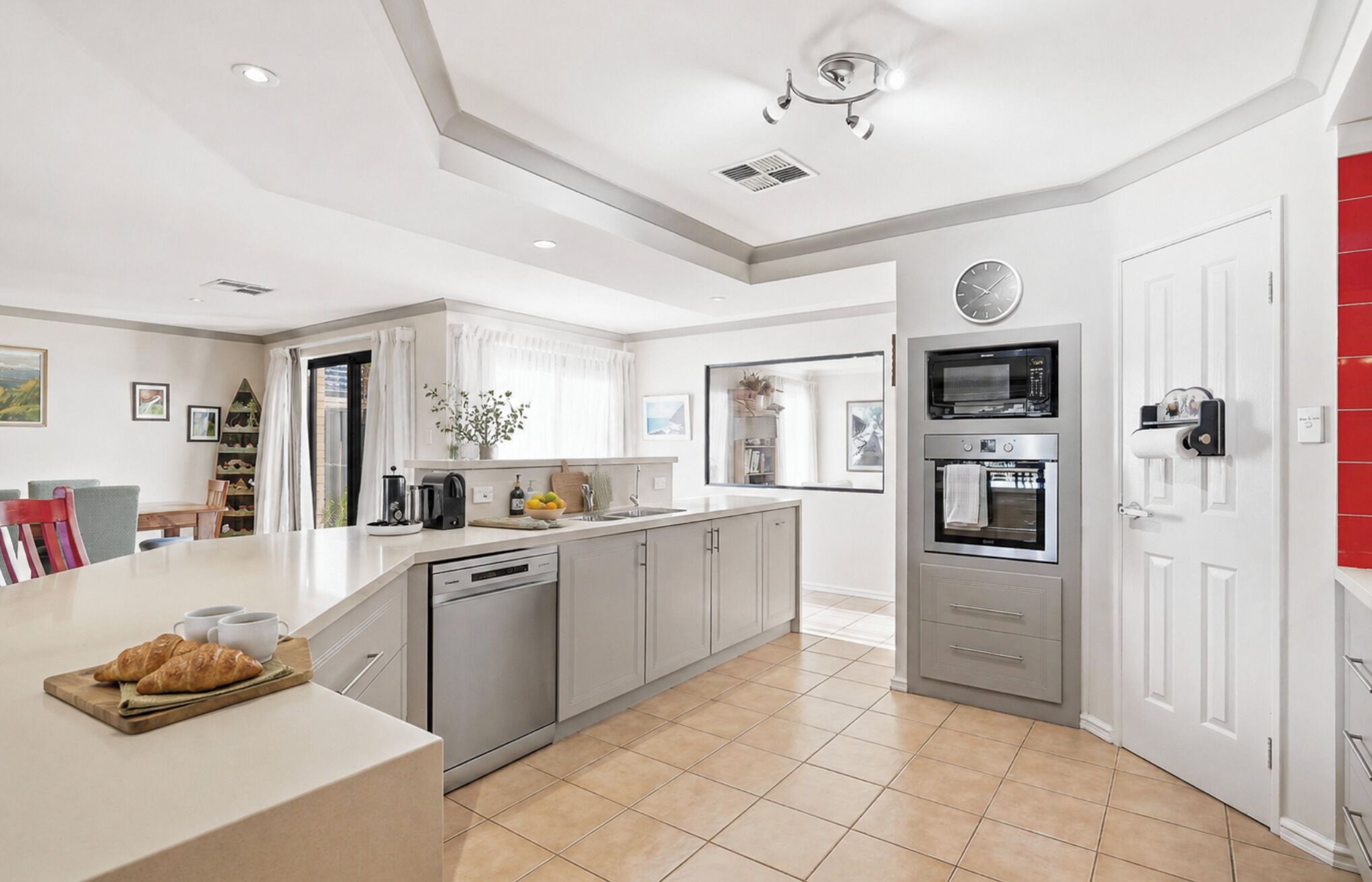 Een moderne keuken met een centraal eiland, ingebouwde apparatuur en een eethoek met stoelen.
