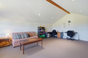 A room with a sofa, a wooden coffee table, a desk with a computer, and a chair. - Murray River family retreat with private pool, kayaks, paddleboards and reserve views (South Yunderup)